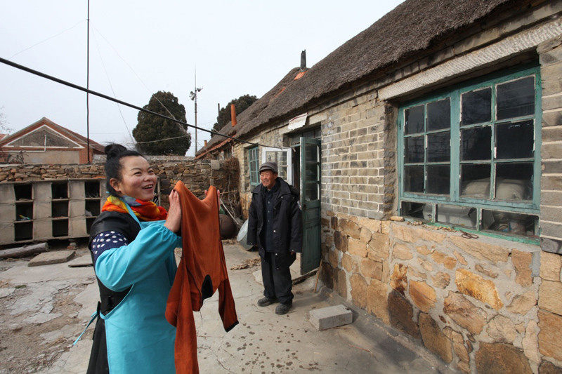 图为：12月14日，在山东省威海市文登区侯家镇崔家村，养老服务中心的服务员李清华（左）来到崔同春老人家，帮助老人清洗晾晒衣物。